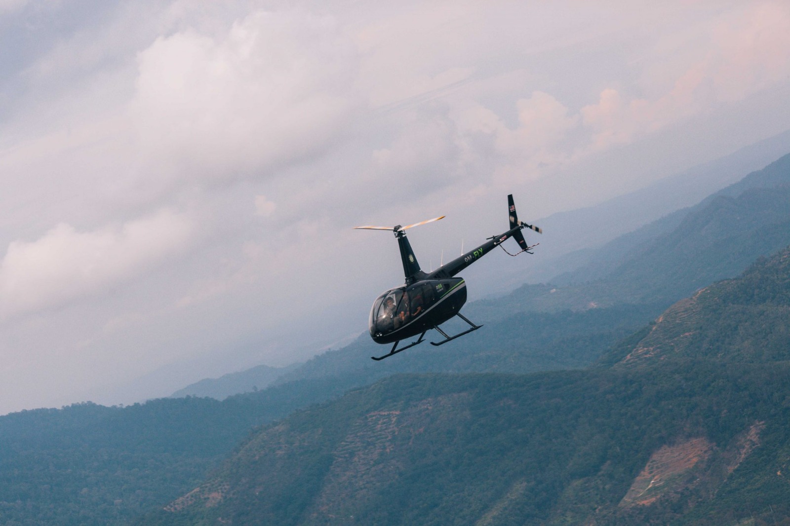 Robinson R44 flying over Malaysian hills